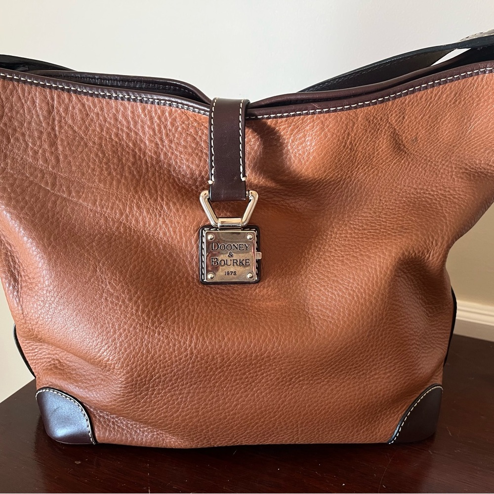 Dooney & Bourke pebble grain caramel leather bucket bag with brown leather trim.